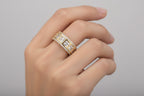 Gold ring with diamond accents on a light gray background