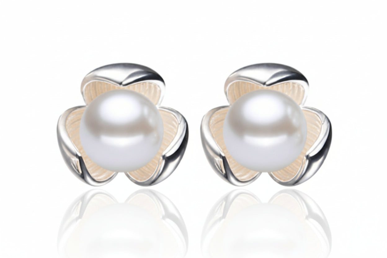 Pair of pearl earrings with silver floral designs on a white background