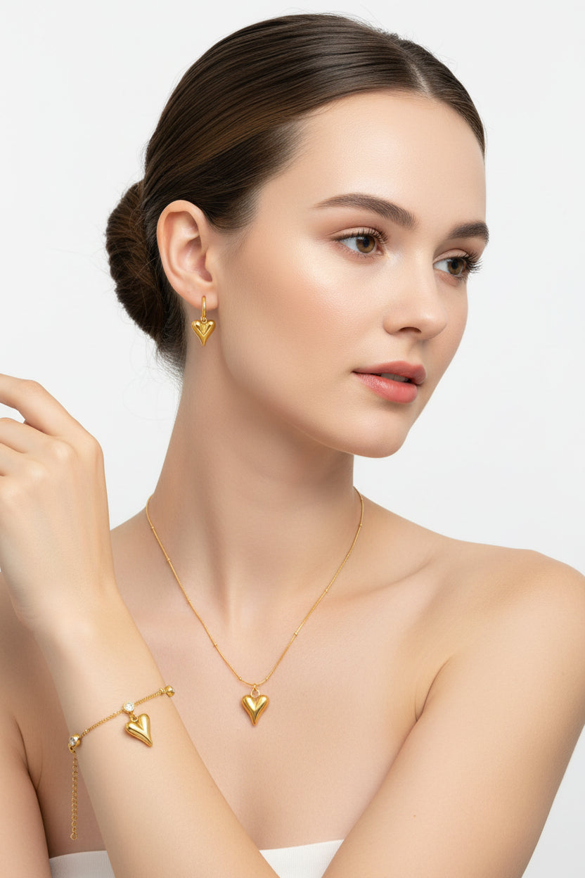 Gold jewelry set including bracelet, necklace, and earrings on a beige background