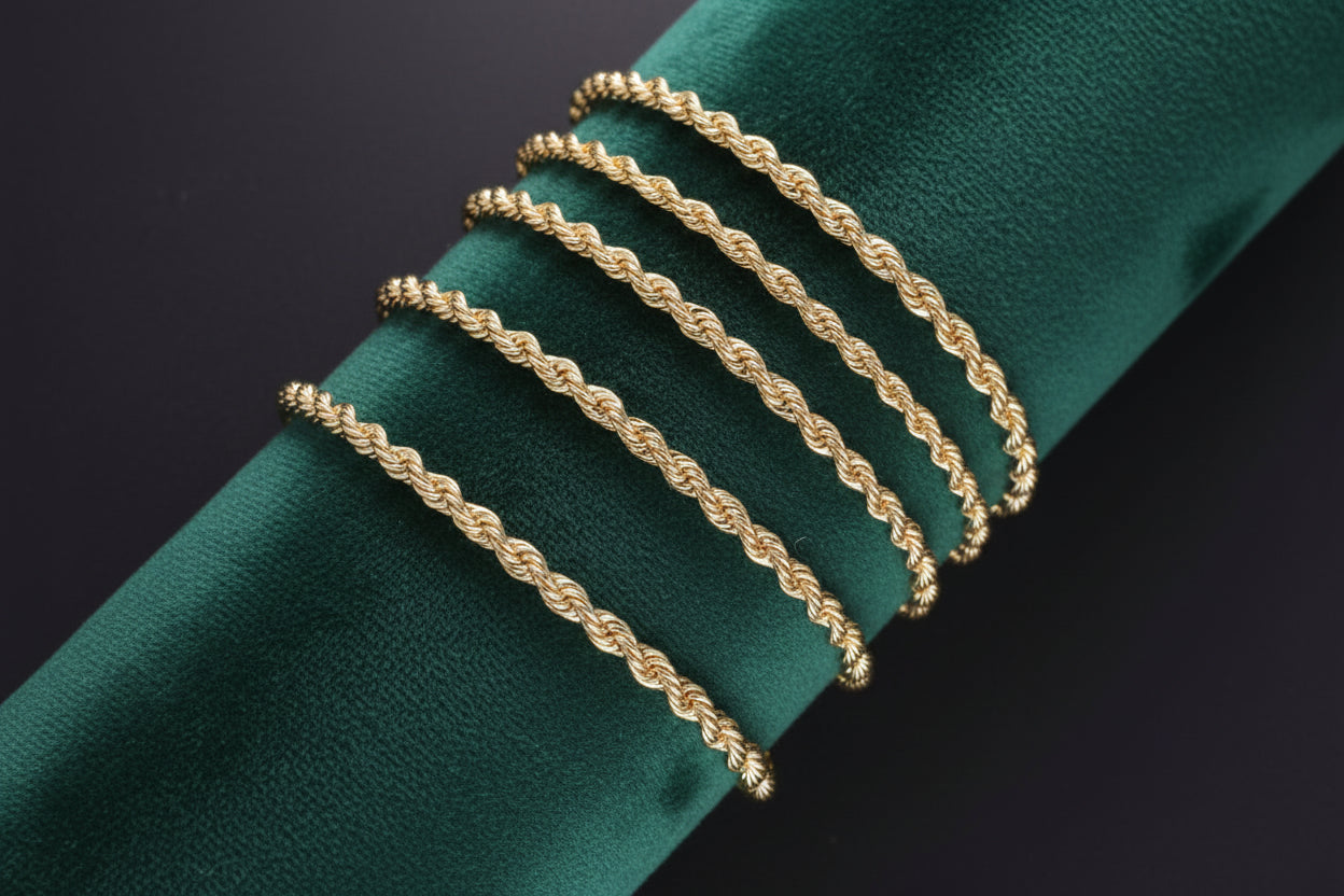 Three gold braided bracelets on a white arm against a black background