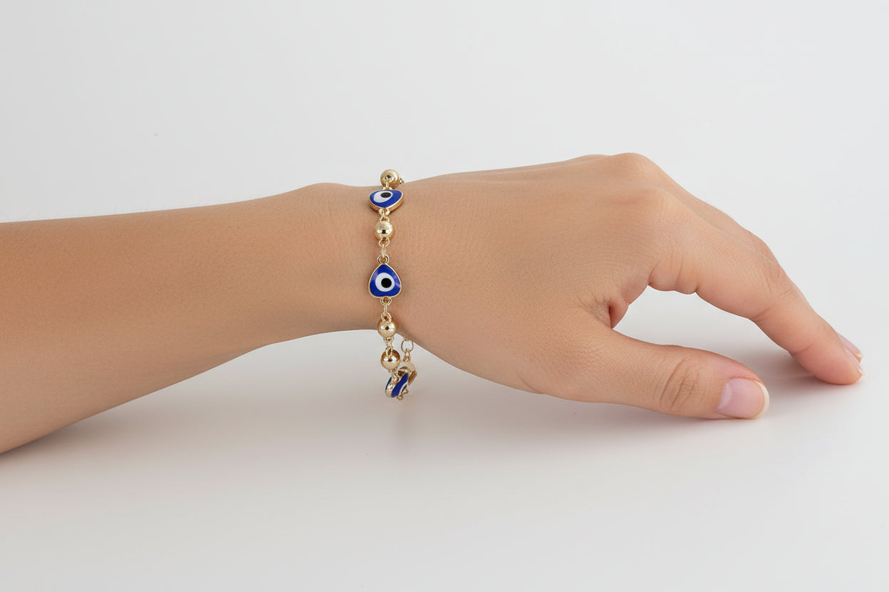 Gold bracelet with blue evil eye charms on a light background