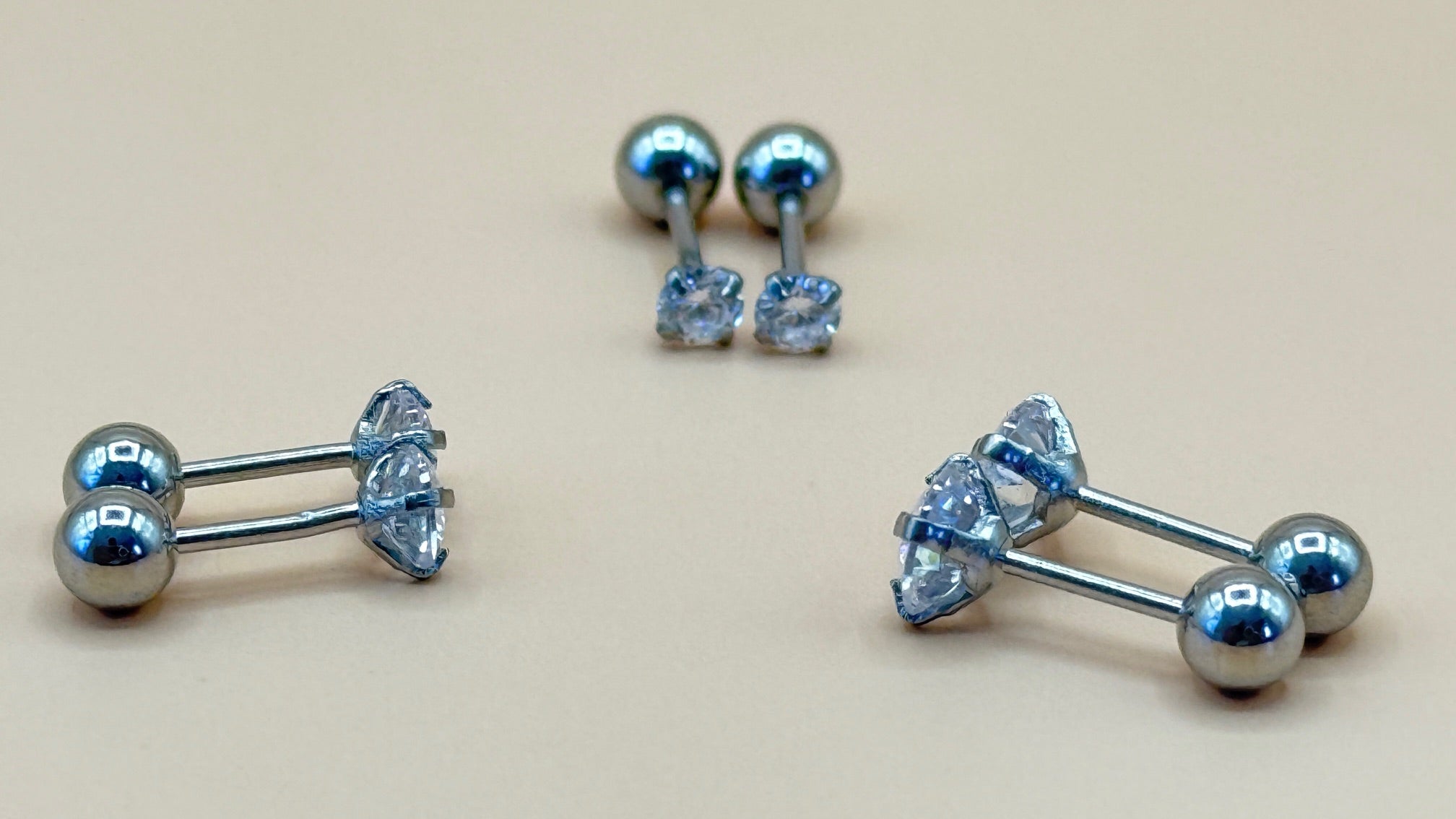 Pair of silver earrings with clear gemstones on a beige background