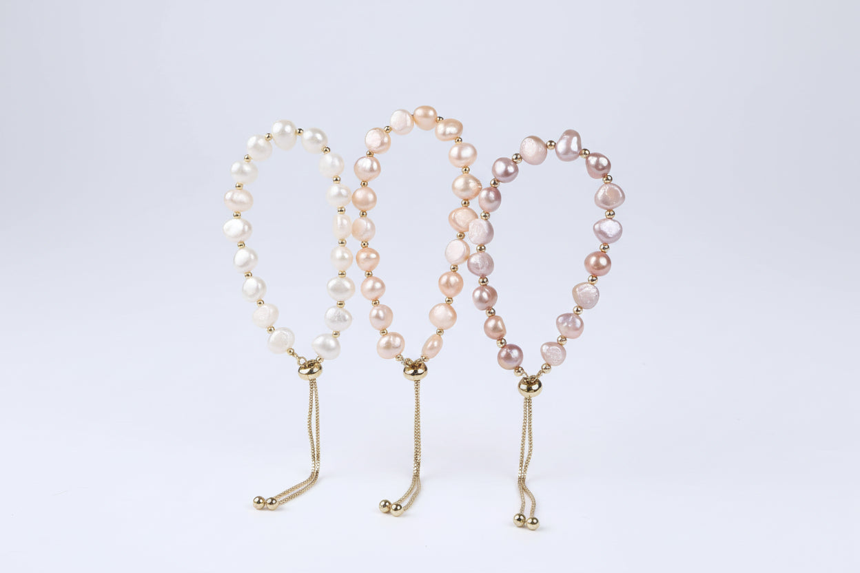 Pearl necklace with gold clasp held in a hand on a white background