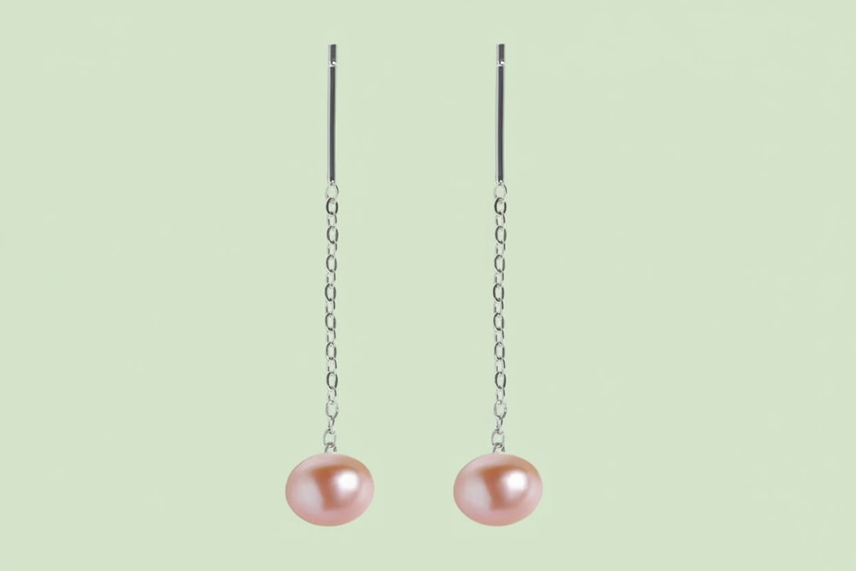 Pair of pink pearl drop earrings on silver chains against a white background