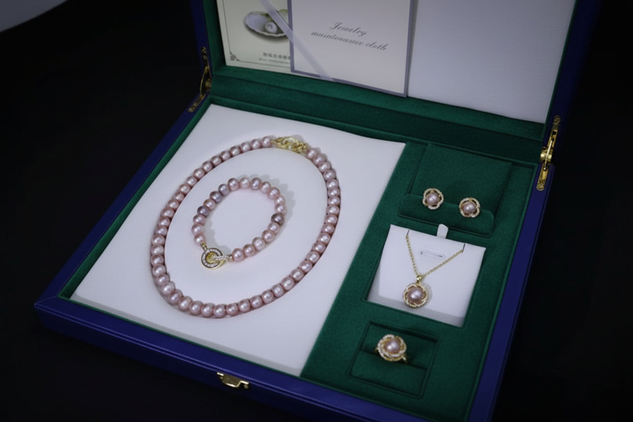 Jewelry set including a pink pearl necklace, earrings, and a pendant in a blue jewelry box.