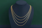 Gold chain necklace on a black mannequin bust against a plain background