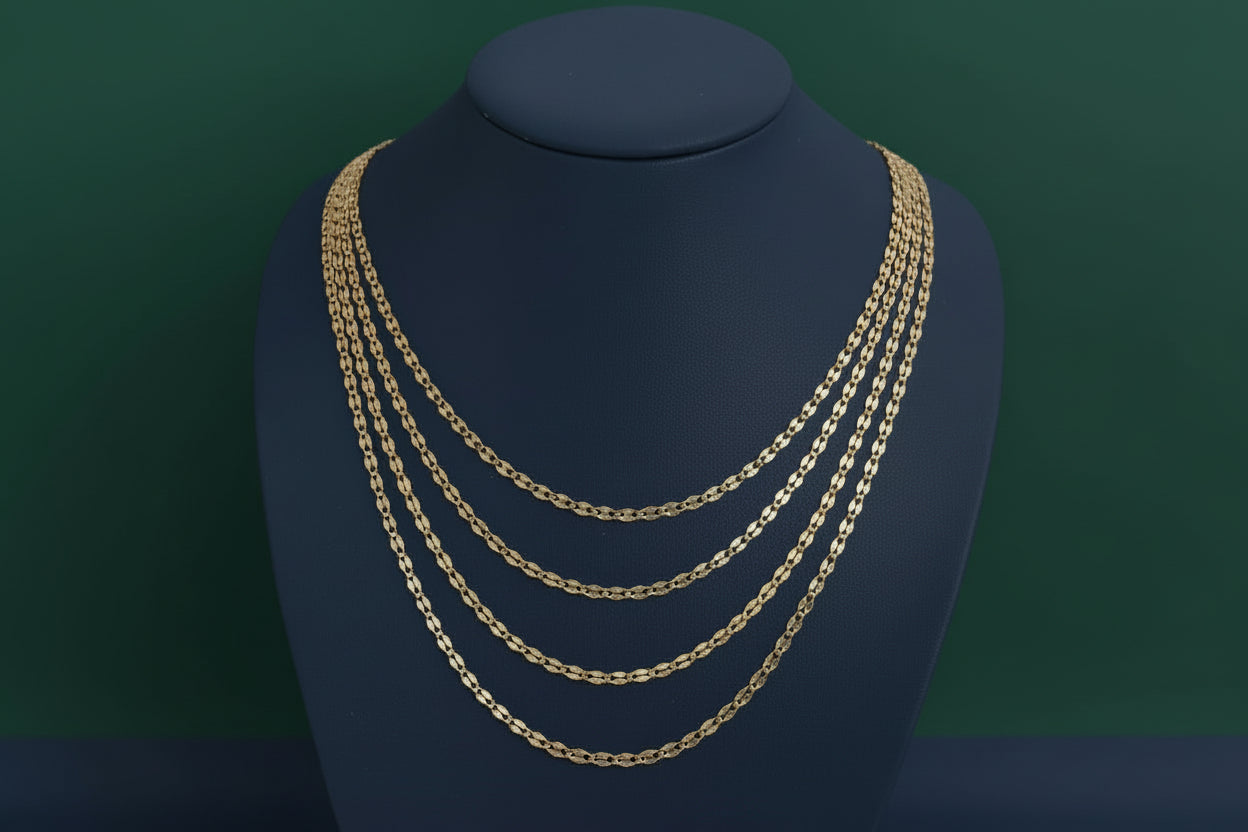 Gold chain necklace on a black mannequin bust against a plain background