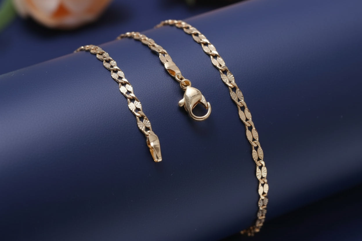 Gold chain bracelet on a white surface with a blurred background