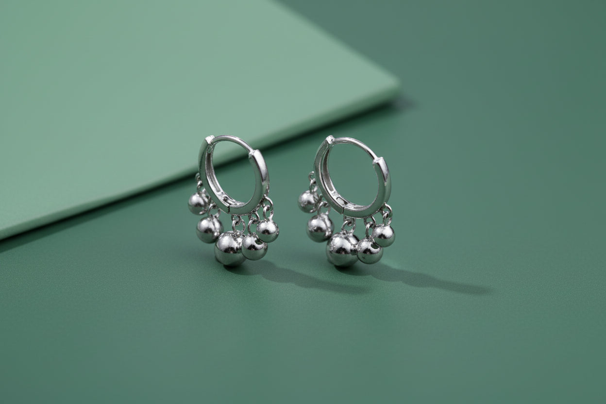 Silver hoop earrings with spherical charms on a white background