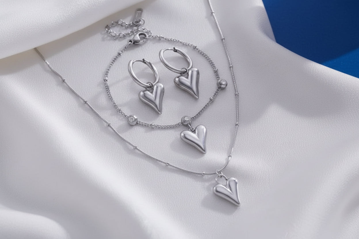 Silver heart-shaped jewelry set on a soft beige background