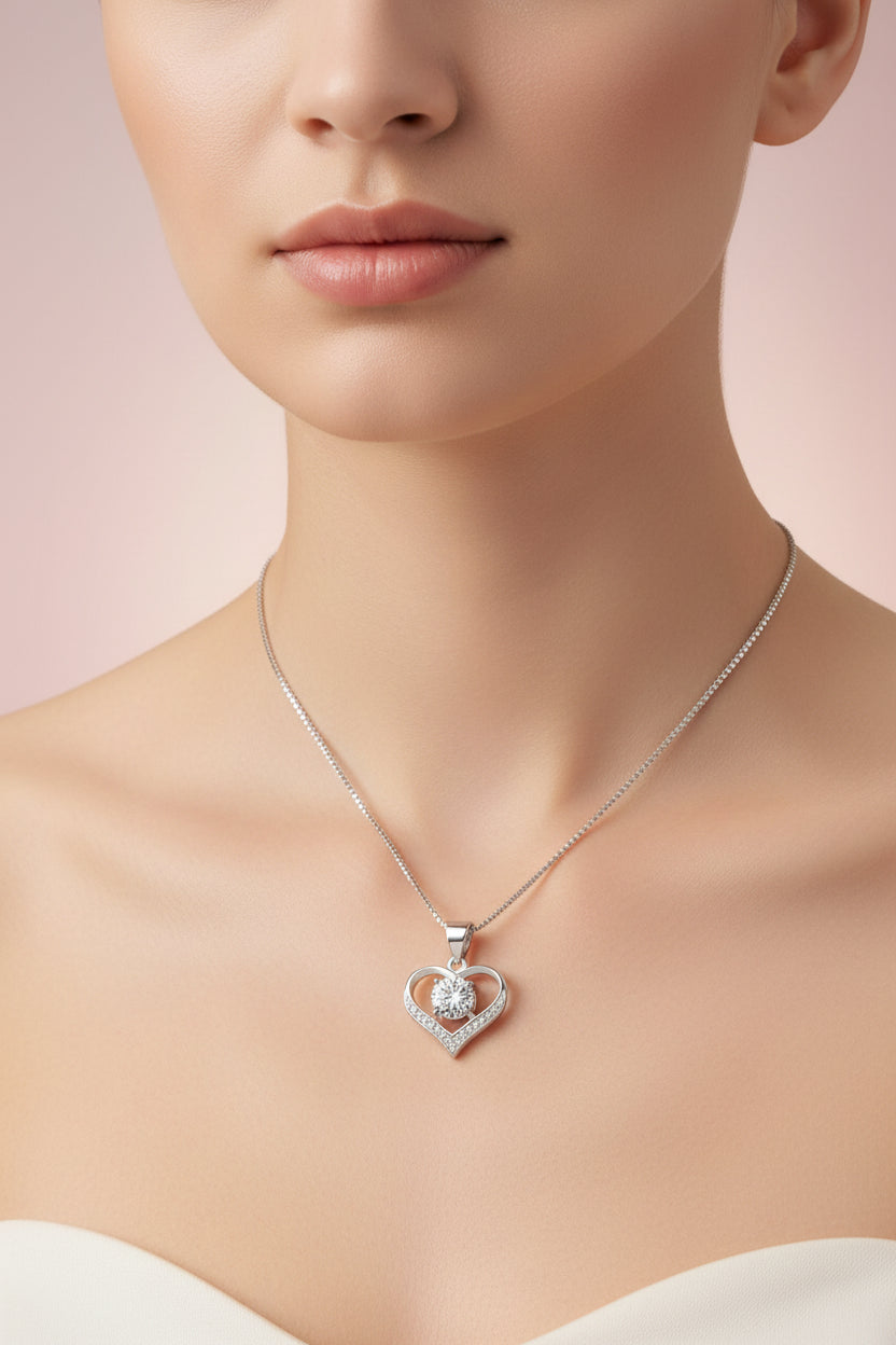 Heart-shaped silver pendant with clear gemstone on a textured dark background