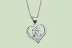 Silver heart-shaped pendant with a diamond on a textured fabric background