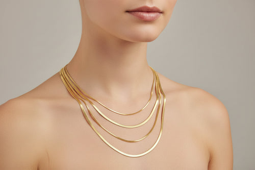 Three gold necklaces on a person's neck against a white background