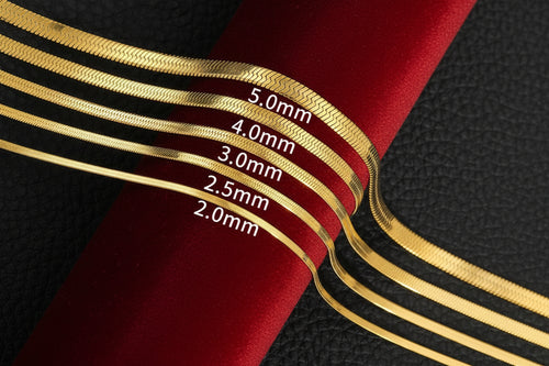 Set of gold bangles with labeled thicknesses on a white cylindrical object against a black textured background.