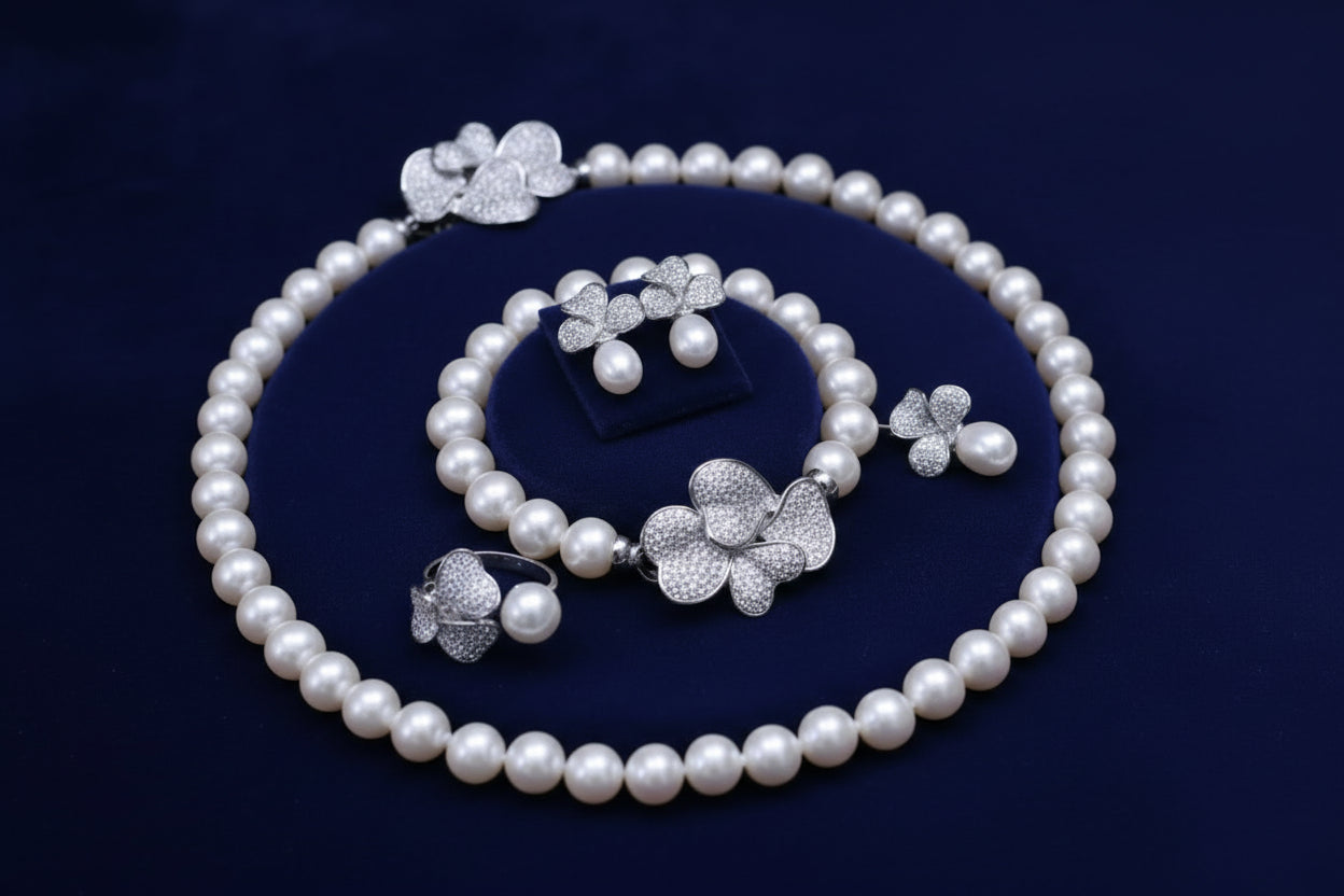 Pearl jewelry set with silver floral pendants on a white heart-shaped box.