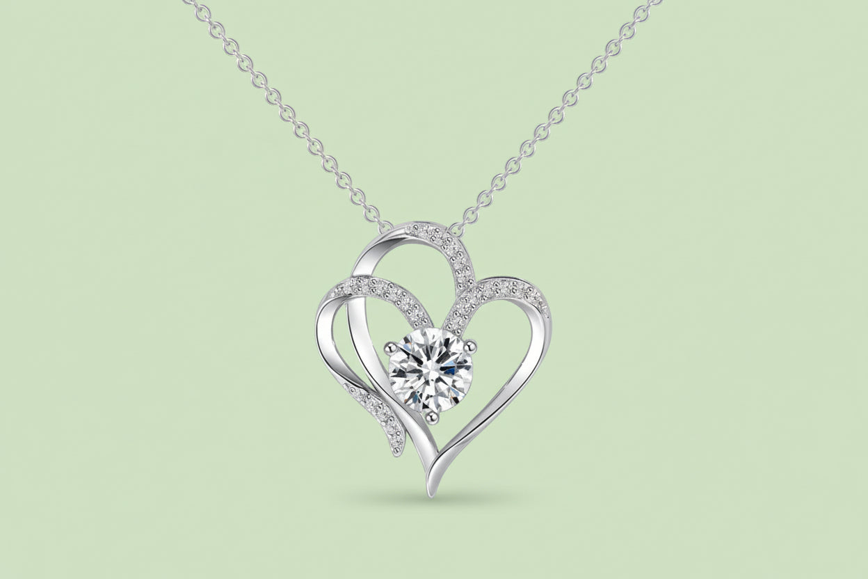 Silver heart-shaped necklace with a central gemstone on a white background