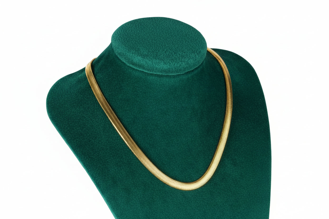 Gold necklace on a mannequin bust against a white background